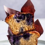 A blueberry muffin cut in half stacked on top of each other.