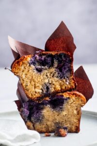 A blueberry muffin cut in half stacked on top of each other.