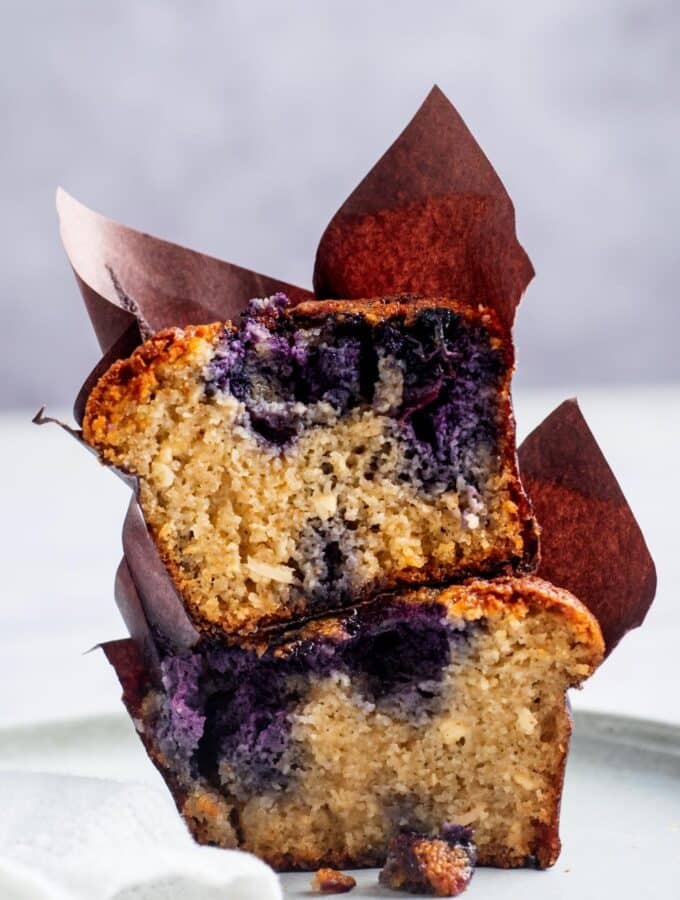 A blueberry muffin cut in half stacked on top of each other.