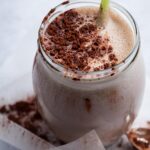 A glass that is filled with a mass gainer shake with cocoa powder on top.