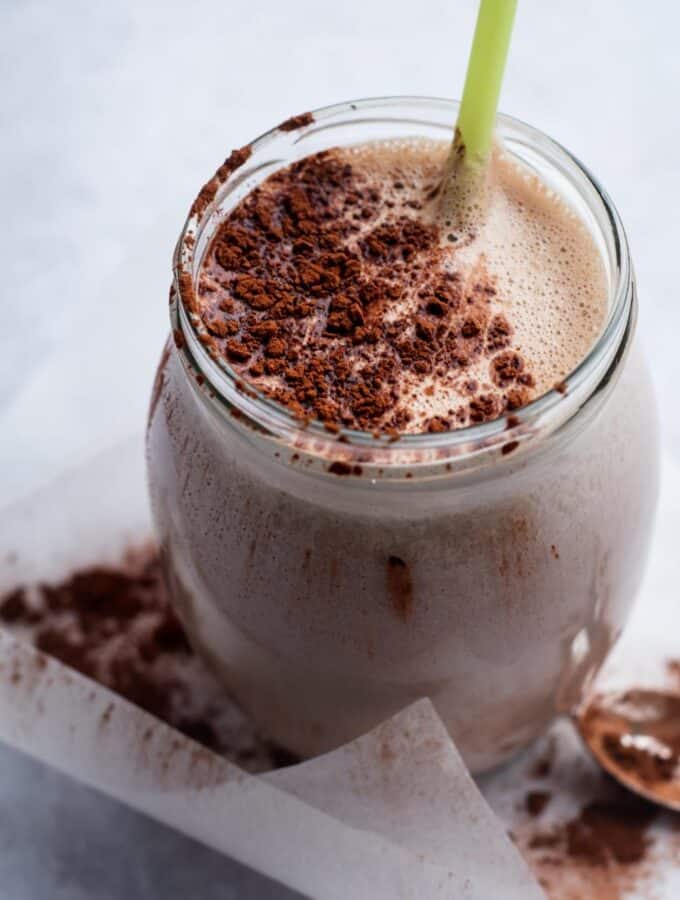 A glass that is filled with a mass gainer shake with cocoa powder on top.