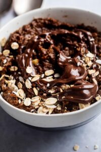 Nutella and oats on top of protien oatmeal in a part of a white bowl.