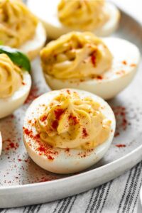 A southern deviled on a plate. Behind it is another deviled egg.