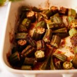 close up of cooked garlic roasted okra in a baking dish on a marble countertop