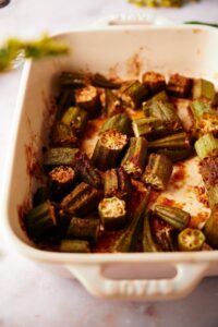 close up of cooked garlic roasted okra in a baking dish on a marble countertop