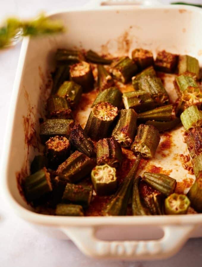 close up of cooked garlic roasted okra in a baking dish on a marble countertop