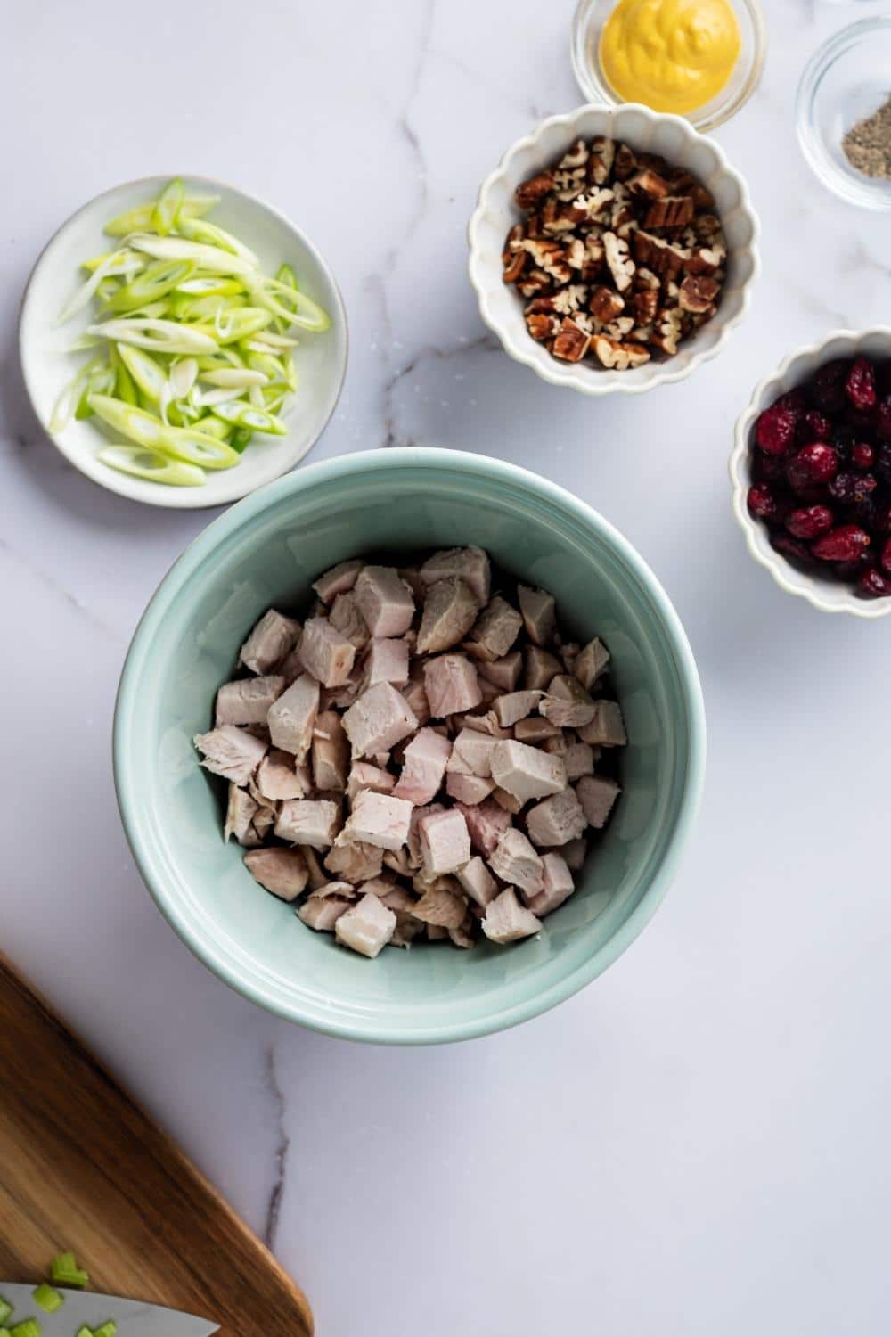 A bowl of diced turkey, a bowl of walnuts, and part of a bowl of cranberries.