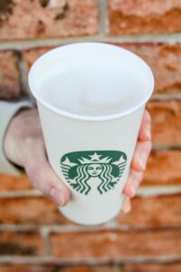 A hand holding a cup of Starbucks keto caramel macchiato.