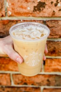 A hand holding a cup of Starbucks iced london fog tea latte.