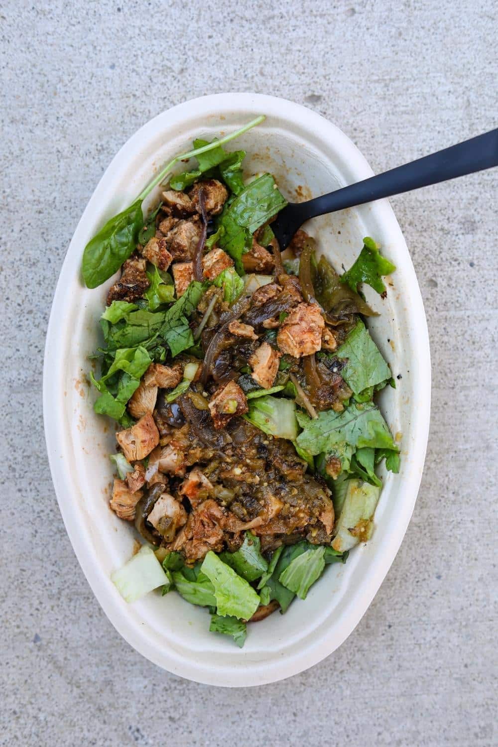 Chicken, green salsa, and lettuce in an oval white bowl.