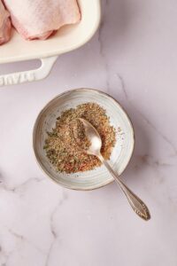 Some seasonings on top of a spoon that is on the seasonings in a bowl.