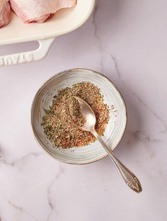 Some seasonings on top of a spoon that is on the seasonings in a bowl.