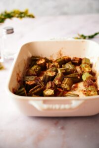 Garlic roasted okra in a white baking dish on a marble countertop