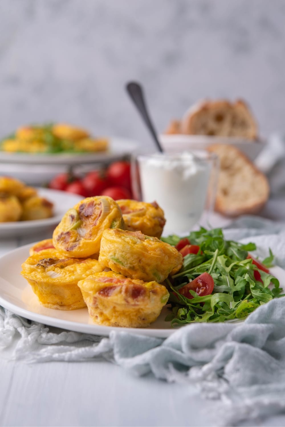 A bunch of egg bites on a white plate. Some of the egg bites are on top of the other.