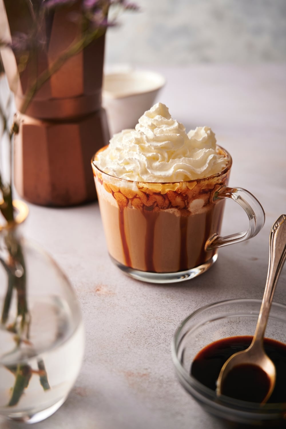 Whipped cream on top of of caramel macchiato in a caramel rimmed glass.