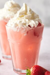 A creamy pink drink in a glass with whipped cream on top.