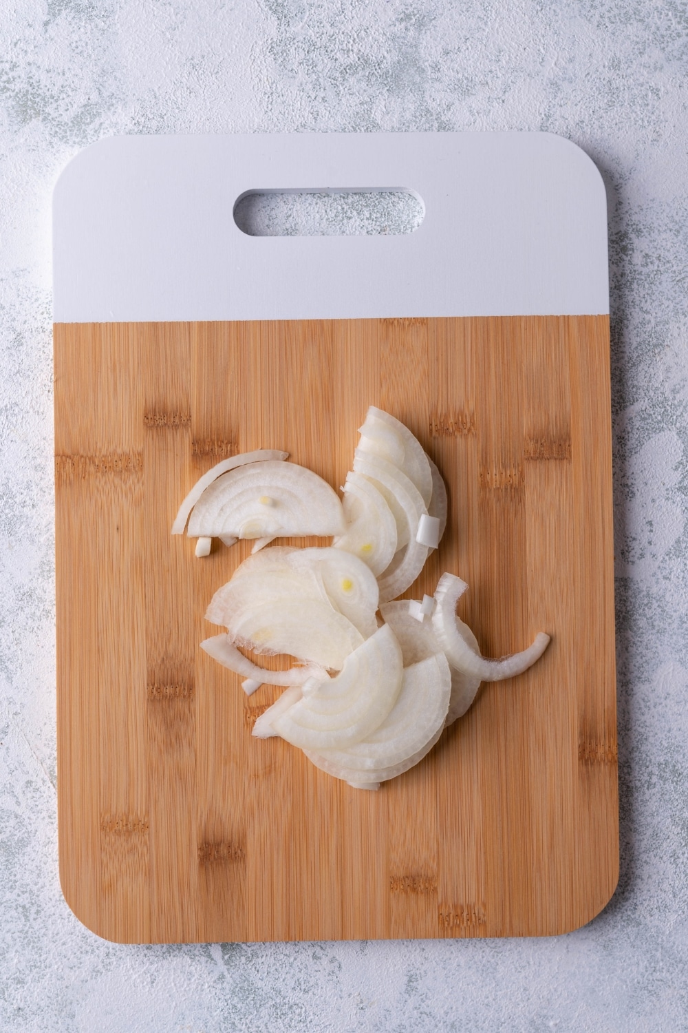 Sliced onion on a bamboo cutting board with a white handle.