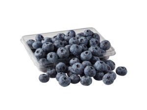 A bunch of blueberries in a container and in front of the container.