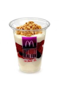 A clear cup filled with granola on top of a layer of yogurt, fruit, and another layer of yogurt.