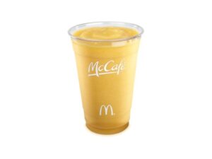 A mango pineapple smoothie in a clear cup that has McCafe written on it.