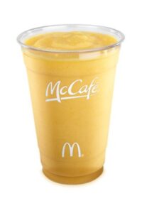 A mango pineapple smoothie in a clear cup that has McCafe written on it.