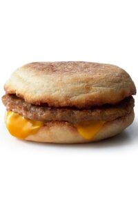 An English muffin with sausage and a slice of American cheese.