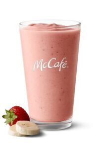 A glass cup with a strawberry banana smoothie in it.