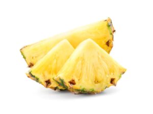 Two slices of pineapple in front of half of a pineapple.