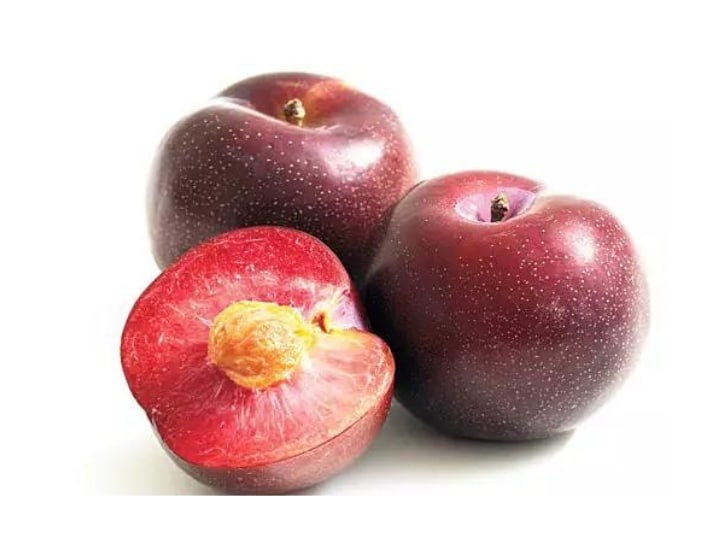 A half of a plum leaning against two whole plums.