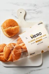 A bag of Hero classic burger buns with a a bun outside of the bag.