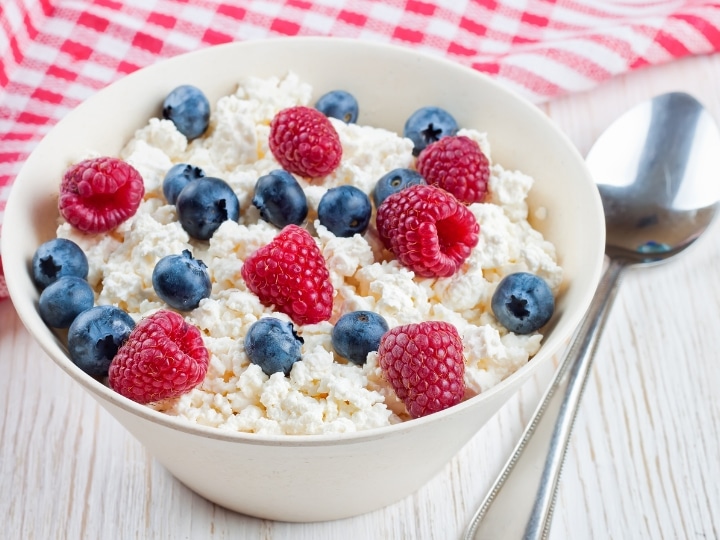 A bowl of cottage cheese with blueberries and raspberries on top.