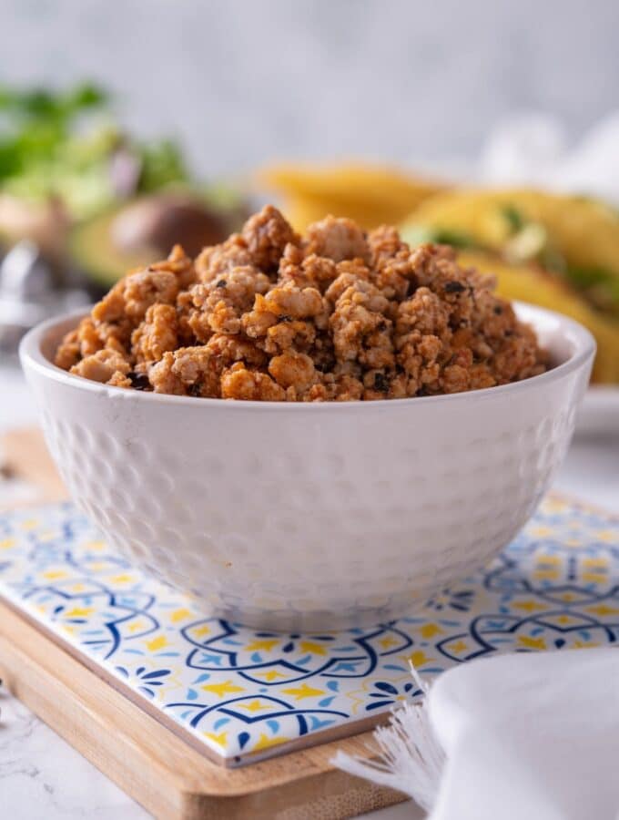 A white bowl filled with seasoned ground turkey.