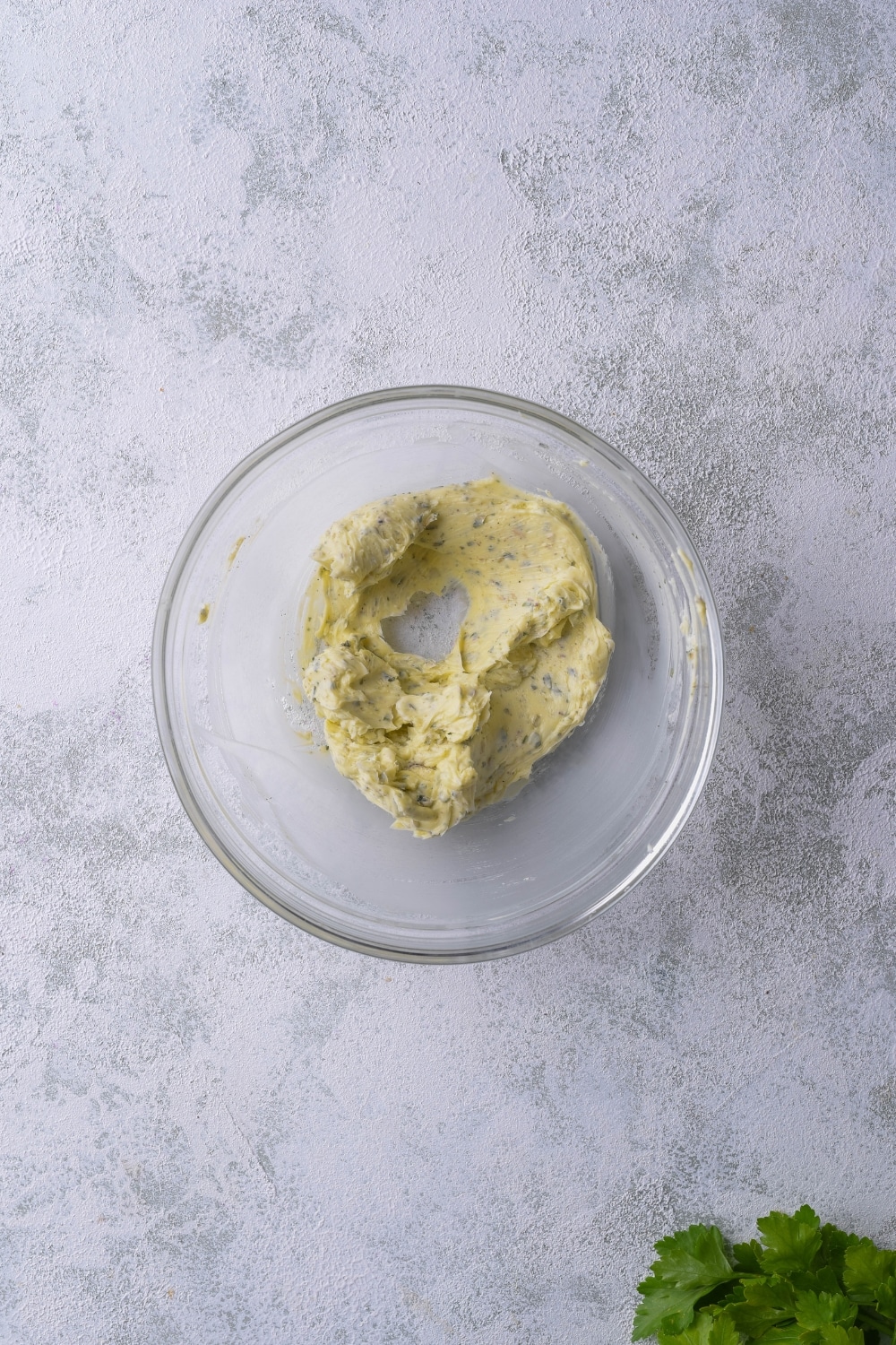 Mixed garlic herb butter in a glass bowl.