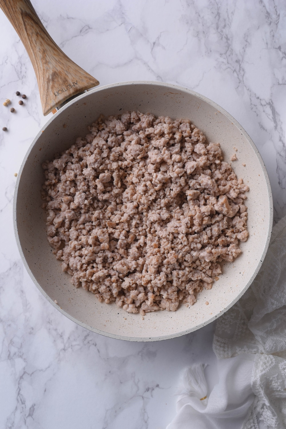 Cooked ground turkey in a white skillet with a wooden handle.