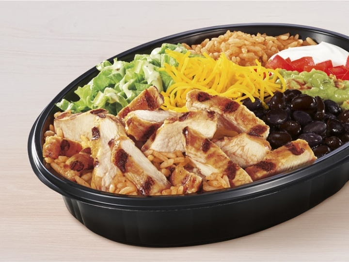 A Taco Bell power bowl with chicken, rice, lettuce, black beas, and shredded cheese.