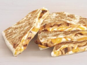 Four slices of Taco Bell cheese quesadilla. Three are stacked on top of one another and one is leaning against the stack.