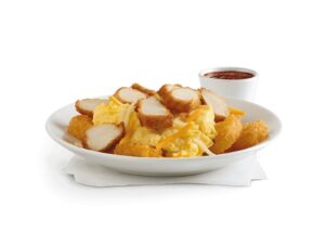 A white plate with scrambled eggs and sliced chicken nuggets on it.