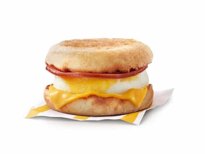 An English muffin with canadian bacon, an eg, and cheese on it.