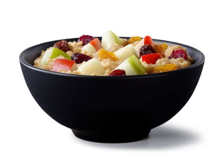 A black bowl filled with oatmeal and fruit.