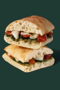 A Starbucks tomato and mozzarella sandwich on focaccia cut in half stacked on top of each other.