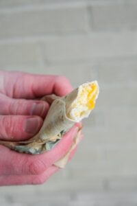 A hand holding a taco bell cheesy roll up.