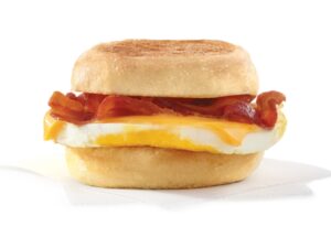 An english muffin with bacon, cheese, and an egg on it.
