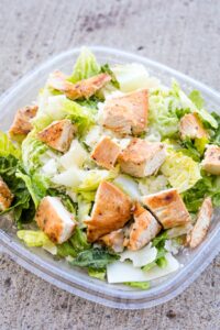 A square container filled with Wendy's chicken caesar salad.
