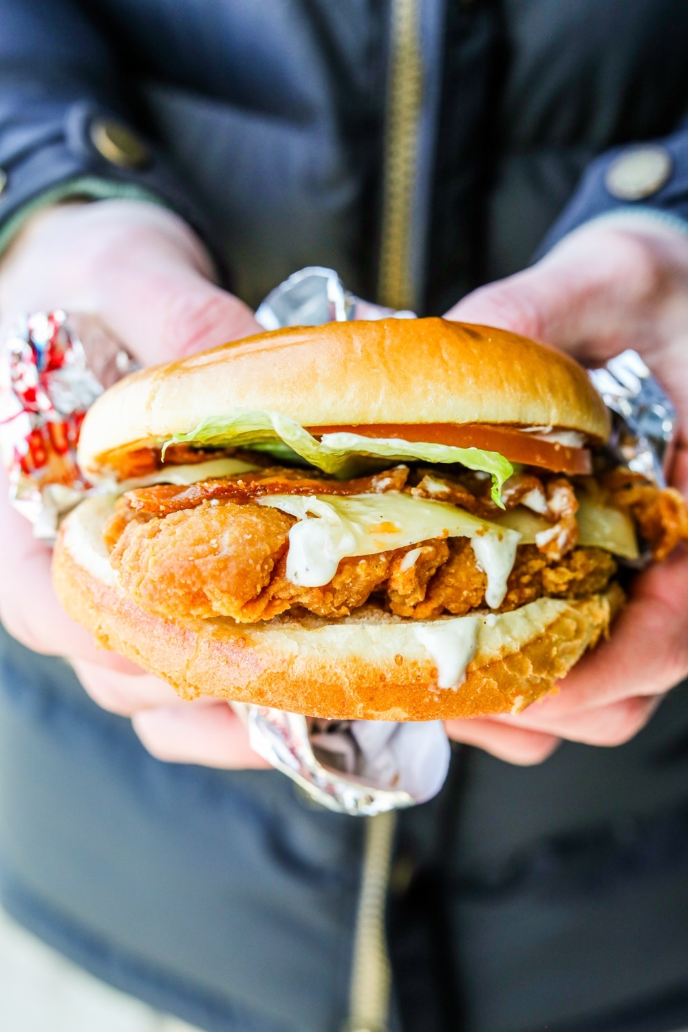 Two hands holding a Wendy's asiago ranch chicken club.