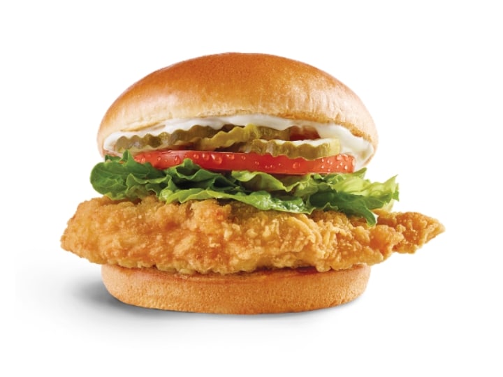 A wendys crispy chicken sandwich with lettuce, tomato, pickles, and mayo.