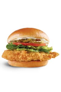 A wendys crispy chicken sandwich with lettuce, tomato, pickles, and mayo.