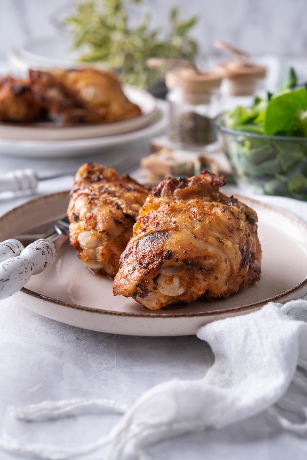 Air fried chicken thighs on a plate with a knife and fork.