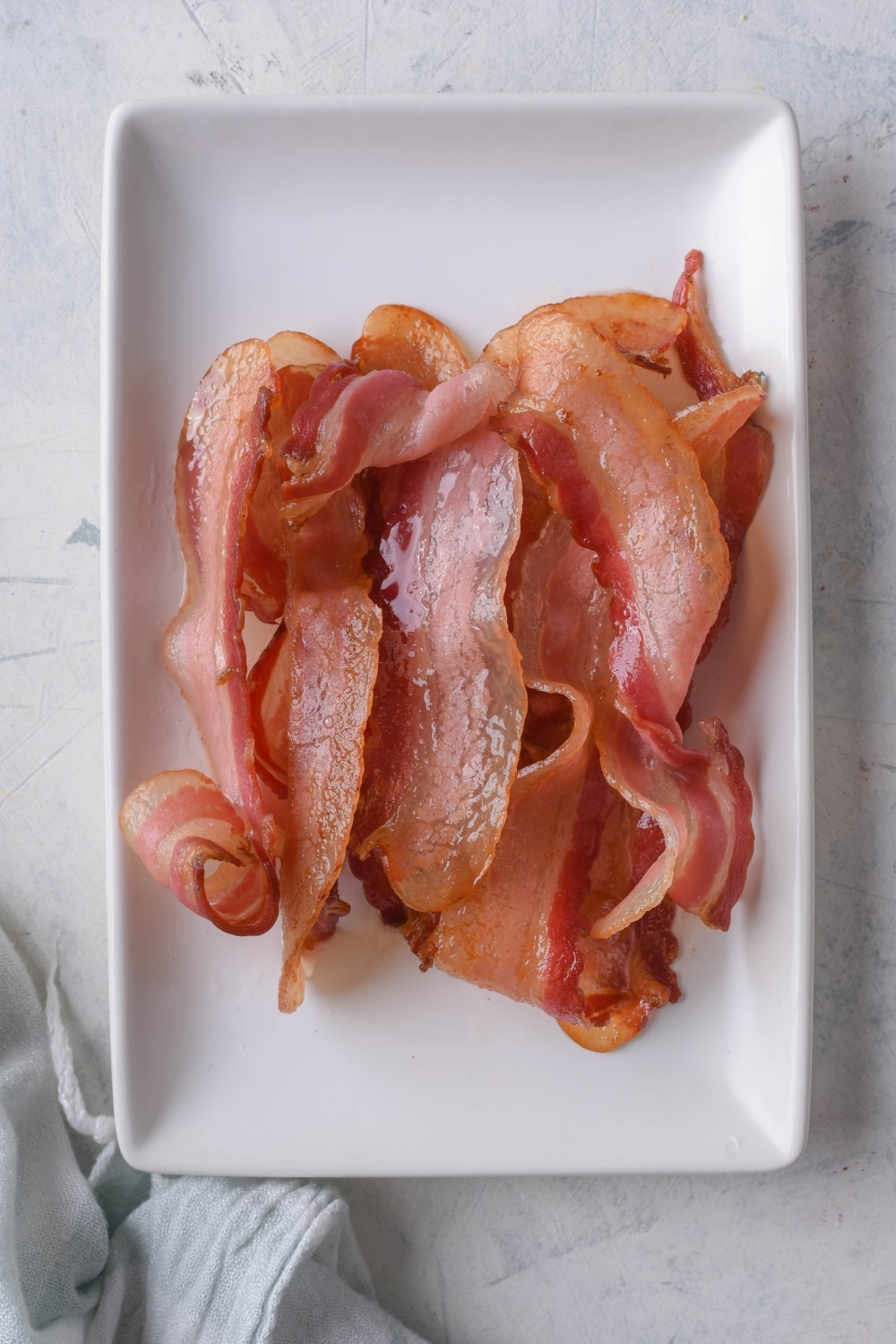 Air fried bacon strips on a rectangle plate.