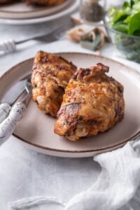 Air fryer chicken thighs on a plate with a knife and fork.