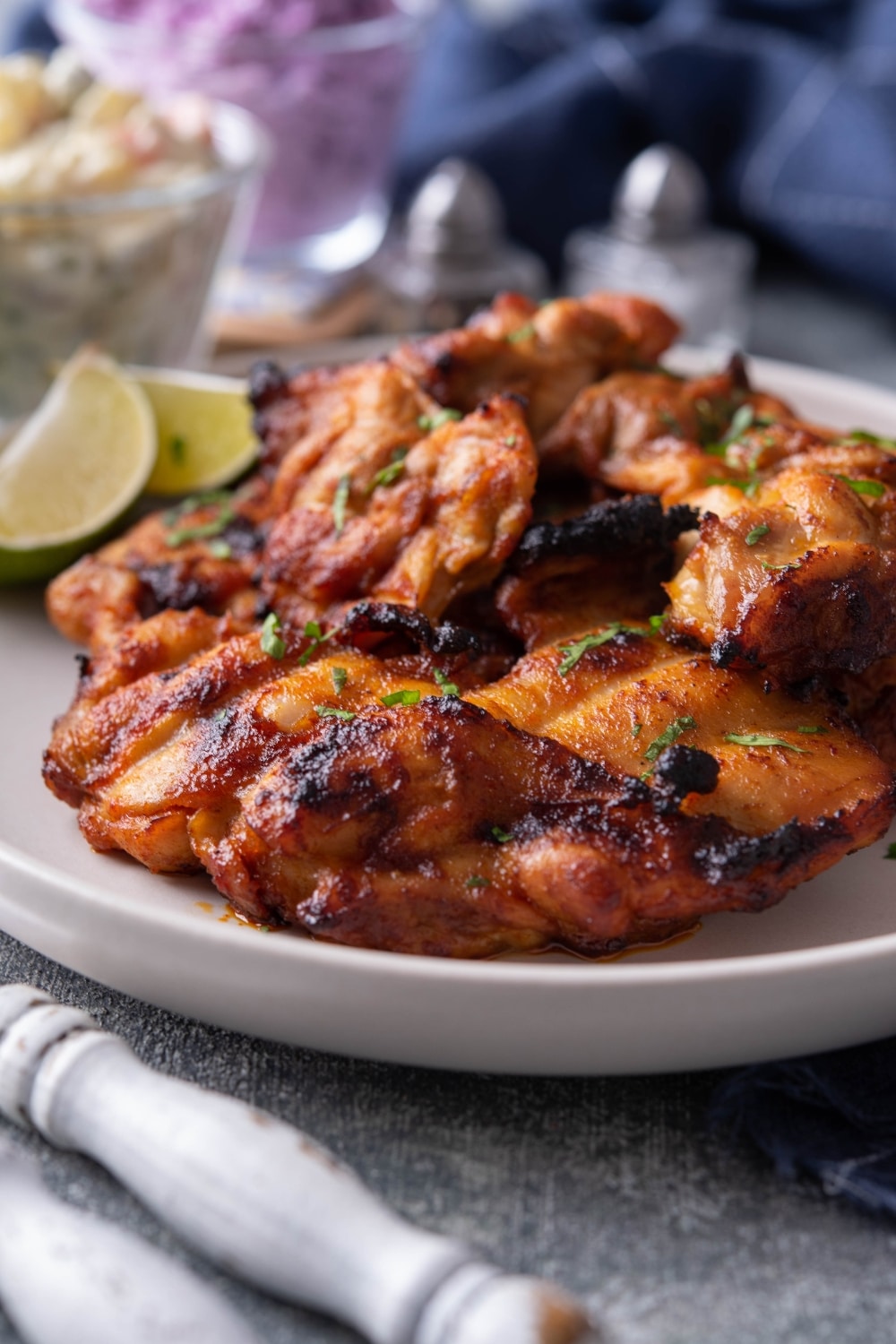 BBQ grilled chicken thighs on part of a white plate.